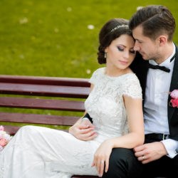 cuplu imbratisat pe-o banca in ziua nuntii, mire si mireasa