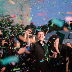 Absolvenți sărbătorind cu confetti la festivitatea de absolvire