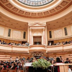 Participanți la ceremonia de absolvire, așezati pe scaune, pregătiți pentru eveniment