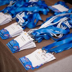 Badge-uri pentru participanți cu numele și panglici albastre